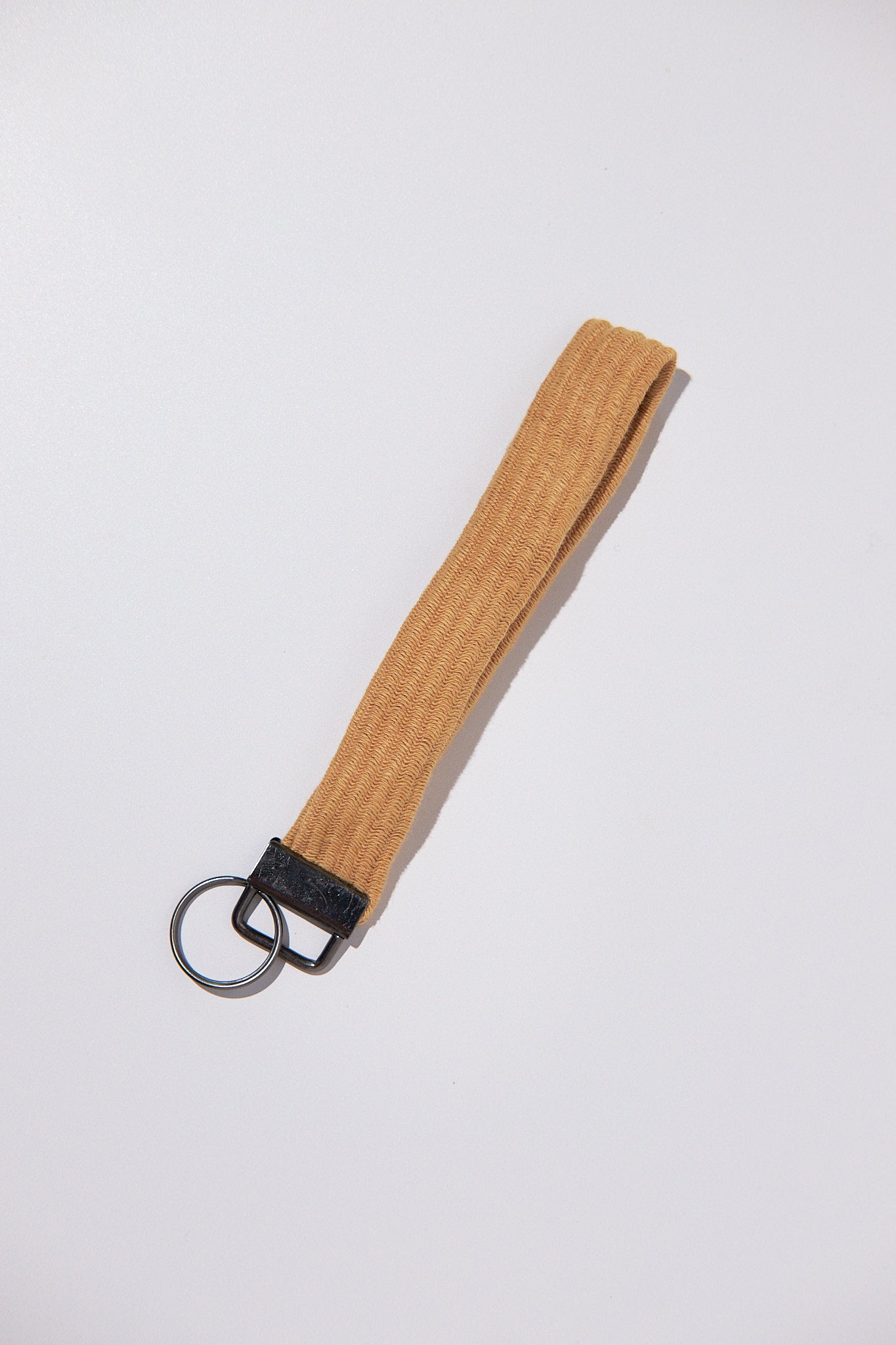 Brown keychain strap upcycled from a sweater with black clip on a white background