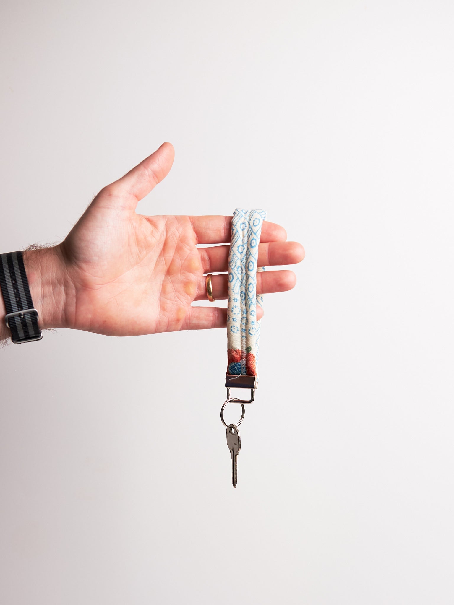 Hand holding a keychain with a key against a plain background