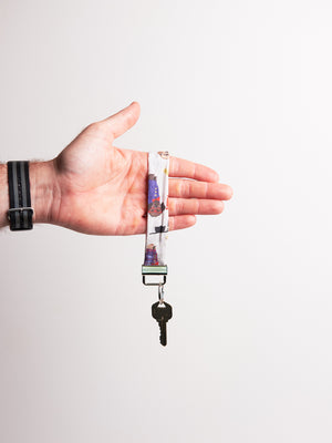 Hand holding a keychain made of fabric with dogs in suits design against a white background