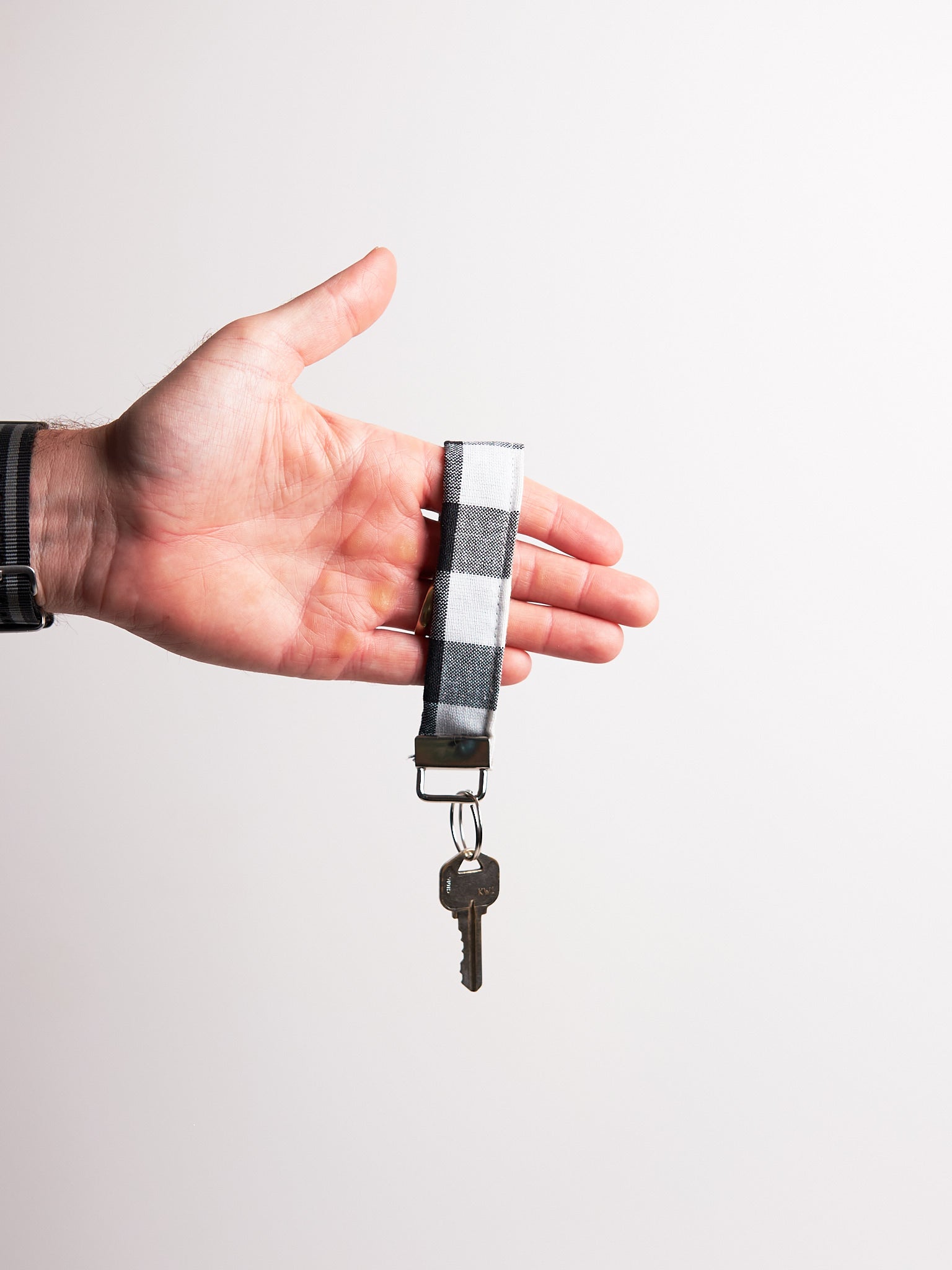 Hand holding a keychain  upcycled from curtains against a plain background