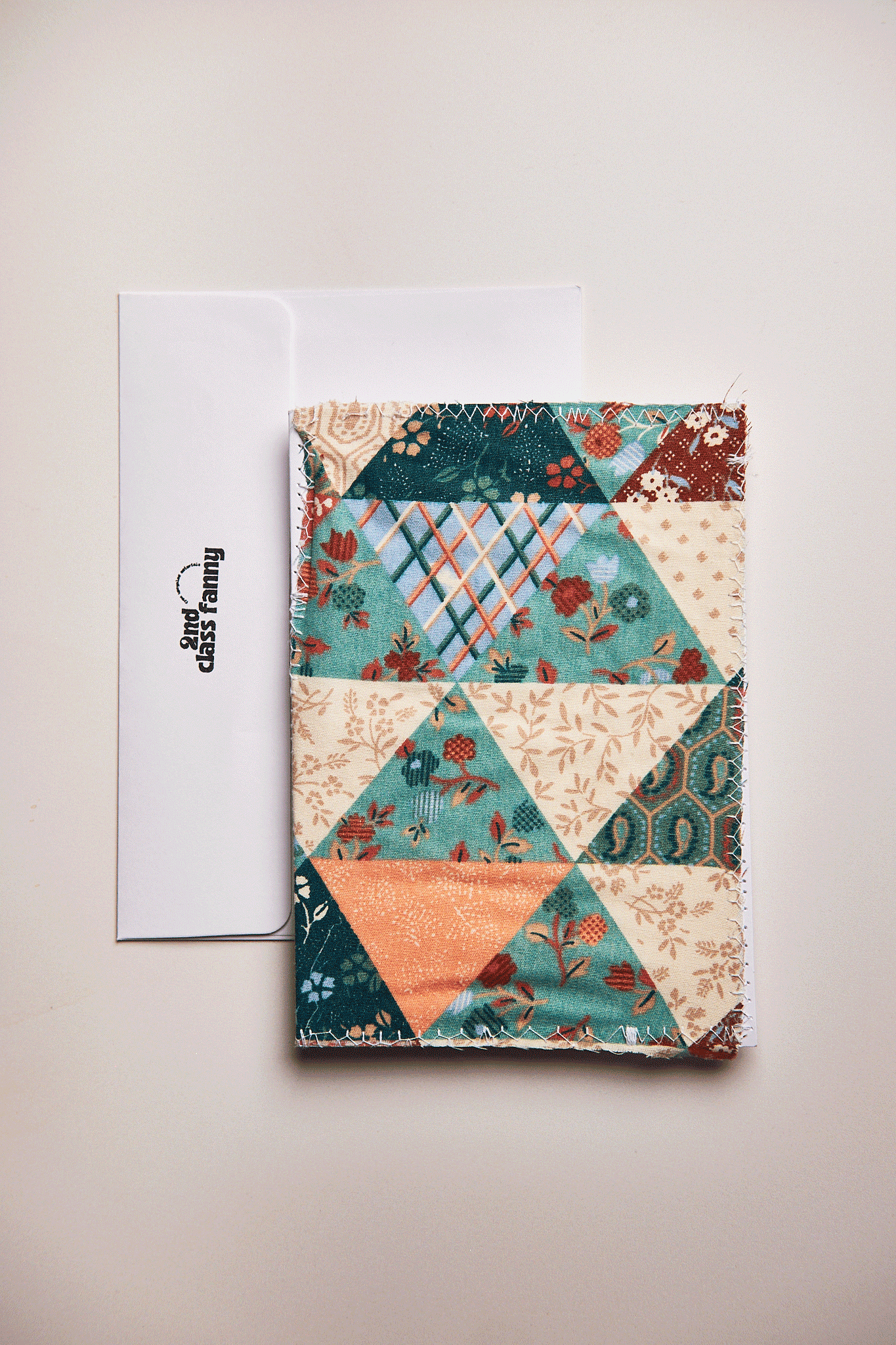 Colorful patchwork upcycled from a bed sheet on a white card on a beige background