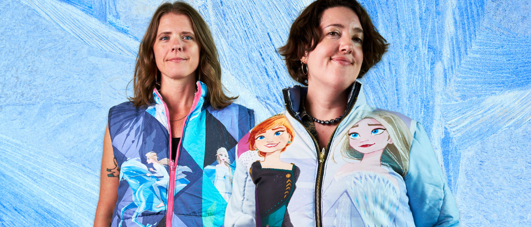 Two women wearing jackets with animated characters from Frozen designs on a blue abstract background