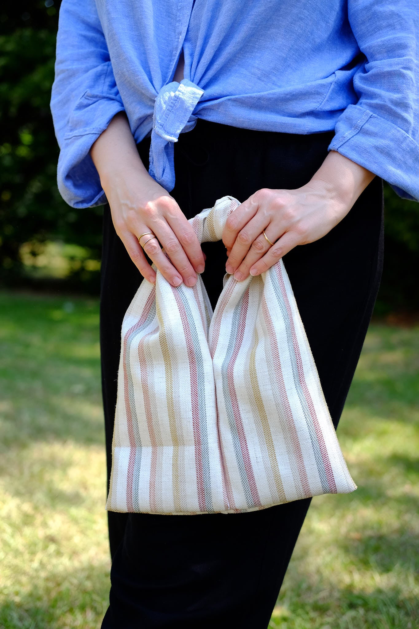 Person holding a multi-stripe knot bag standing in nature