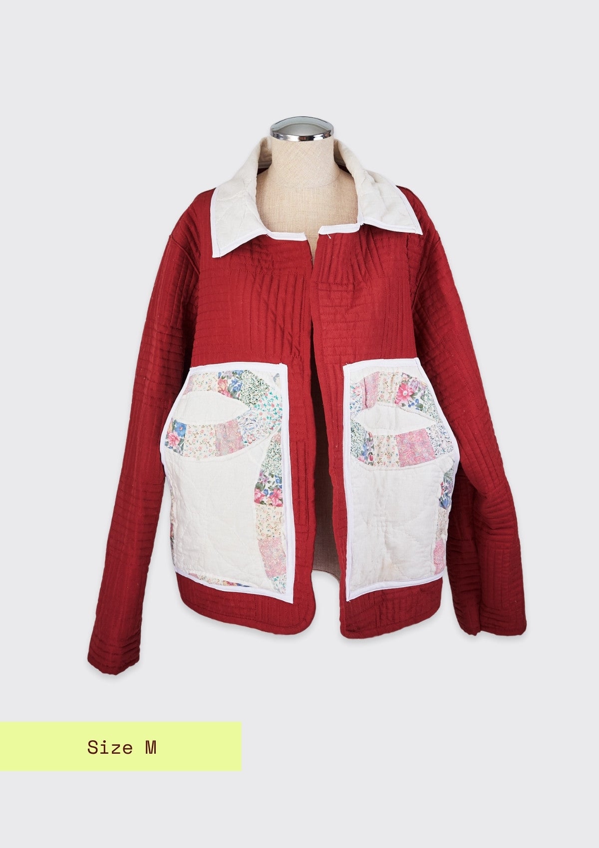 Red jacket upcycled from a quilt with floral patchwork on a mannequin against a white background