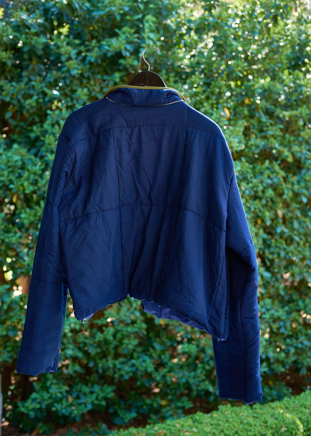 Blue jacket on a hanger against a green leafy background