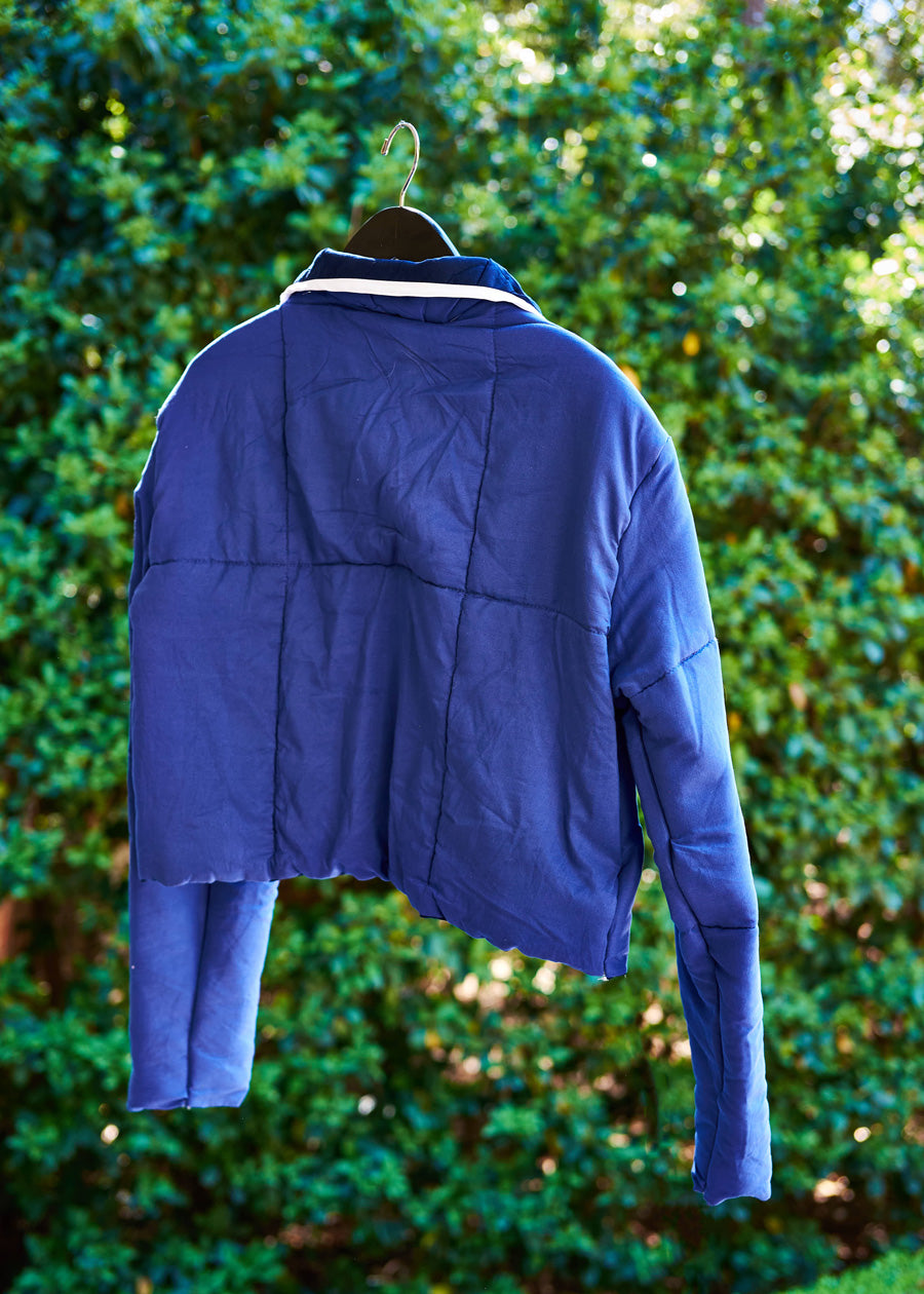 Blue jacket hanging against a green leafy background