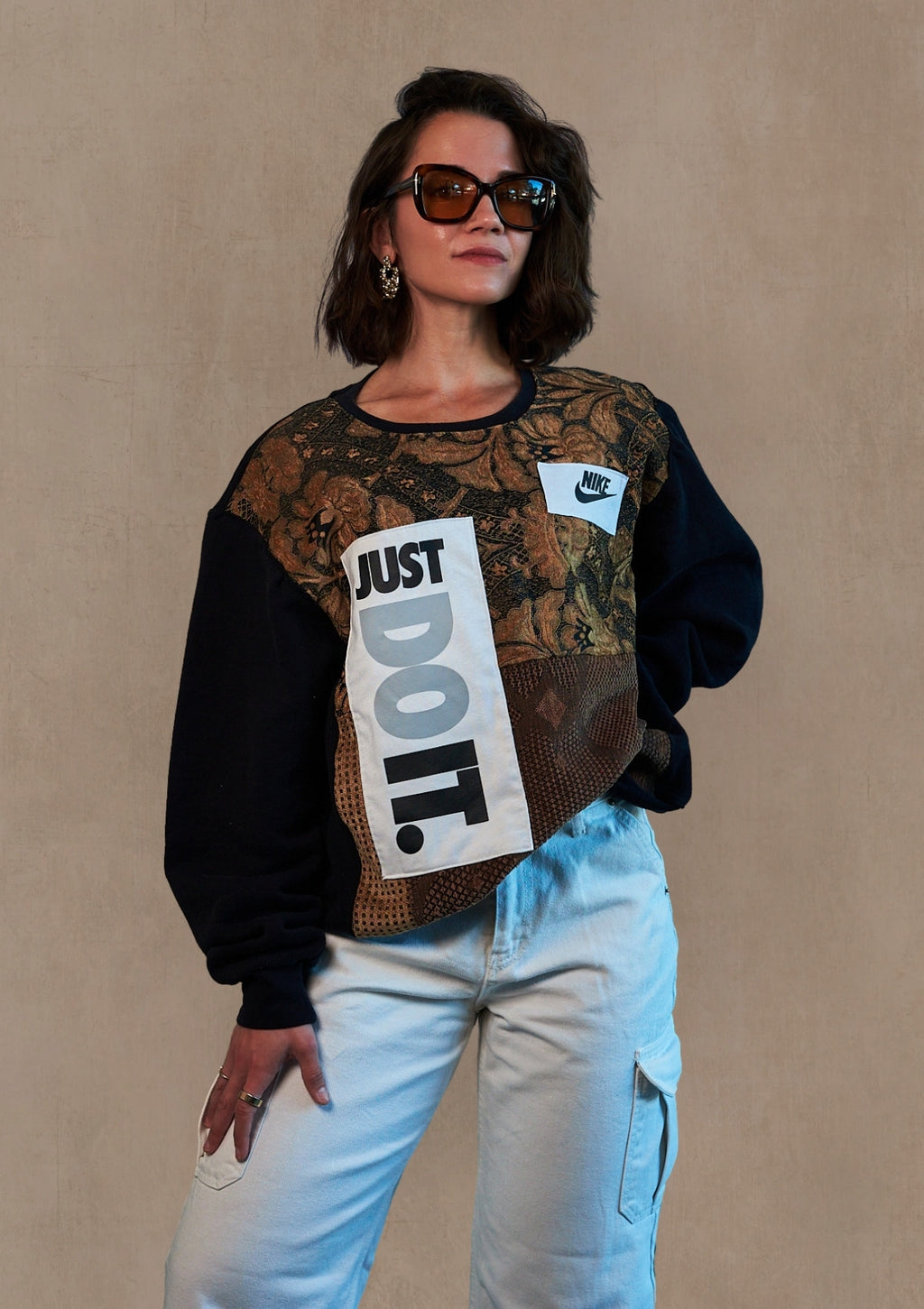 Person wearing a unique pullover sweater upcycled from a crew neck, curtains, and a Nike tank, with text and patterns on a beige background