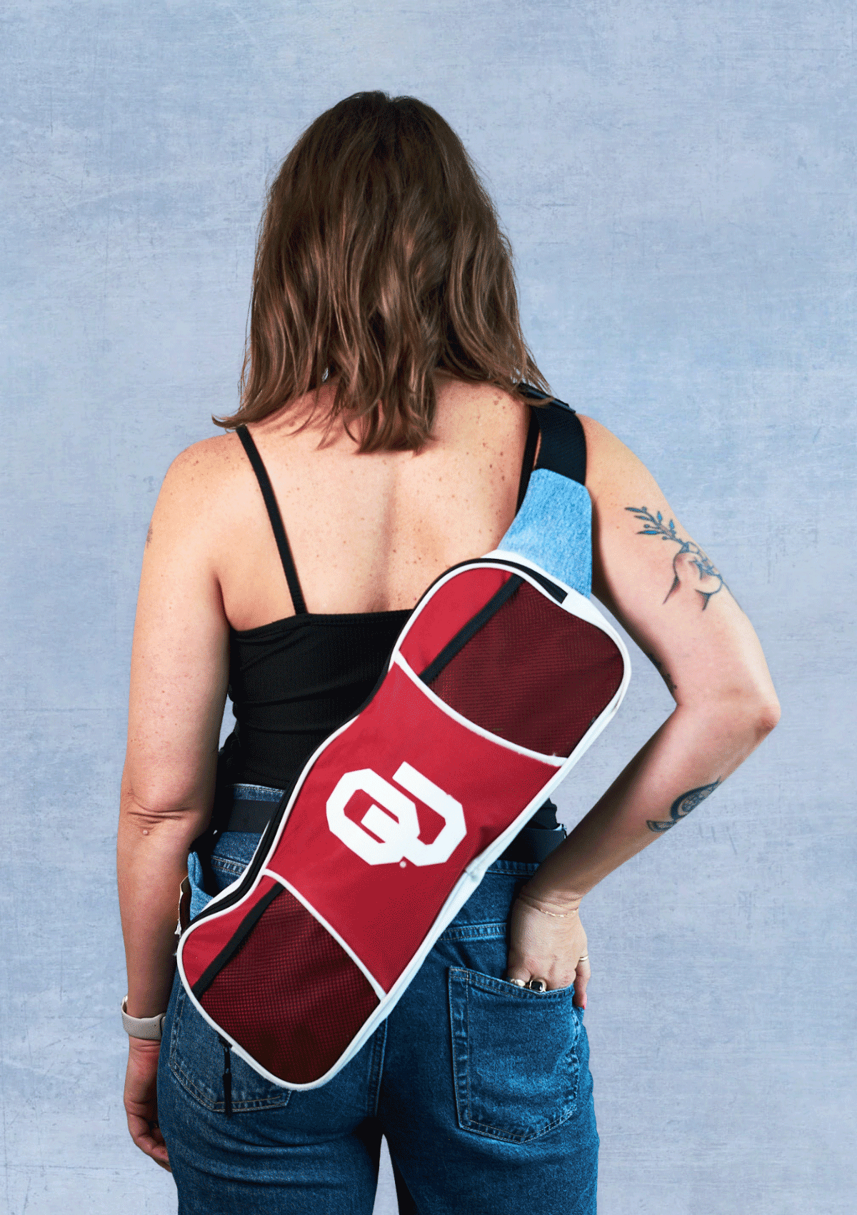 Person wearing a red and white OU bike messenger bag against a blue background