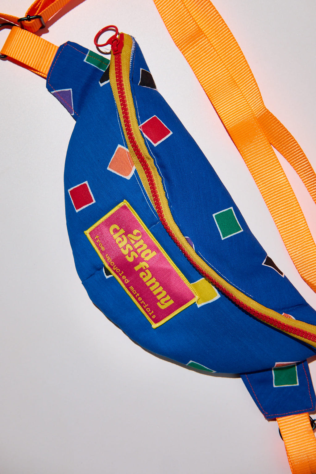 Blue fanny pack with colorful geometric patterns and 'Good Class Fanny' text upcycled from comforter on a light gray background