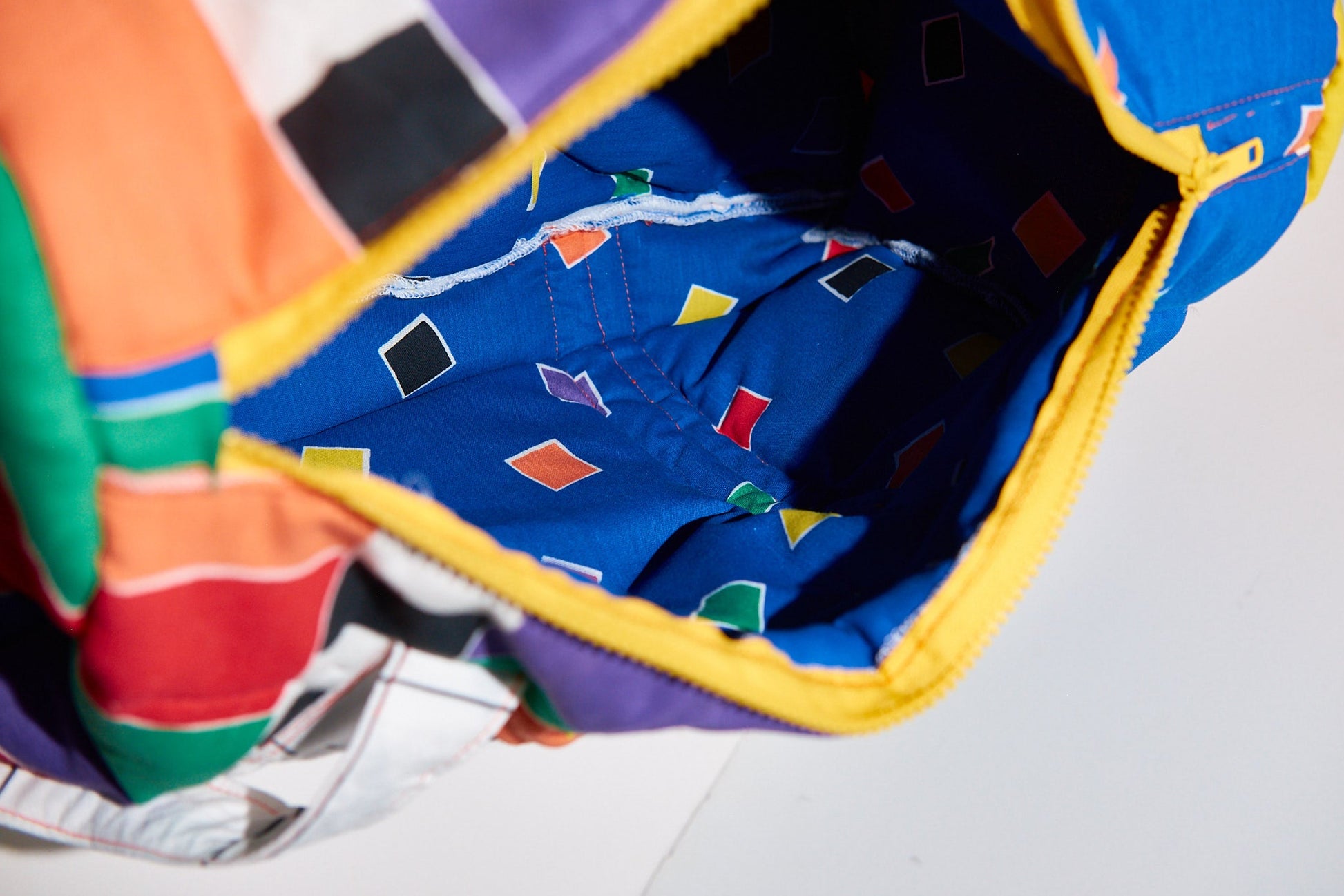 Colorful fabric with geometric patterns inside a bag upcycled from comforter on a white background