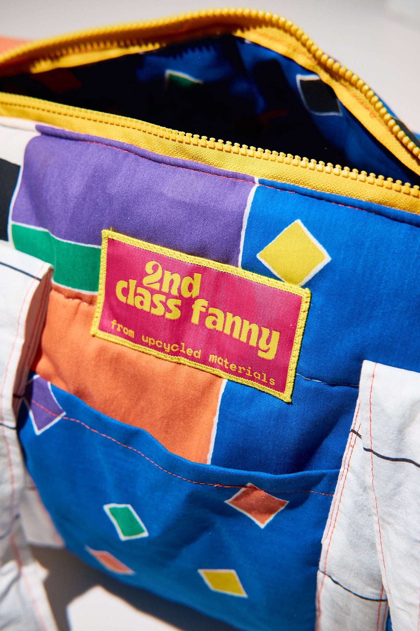 Colorful fabric with a patch labeled '2nd Class Fanny' upcycled from comforter on a white background
