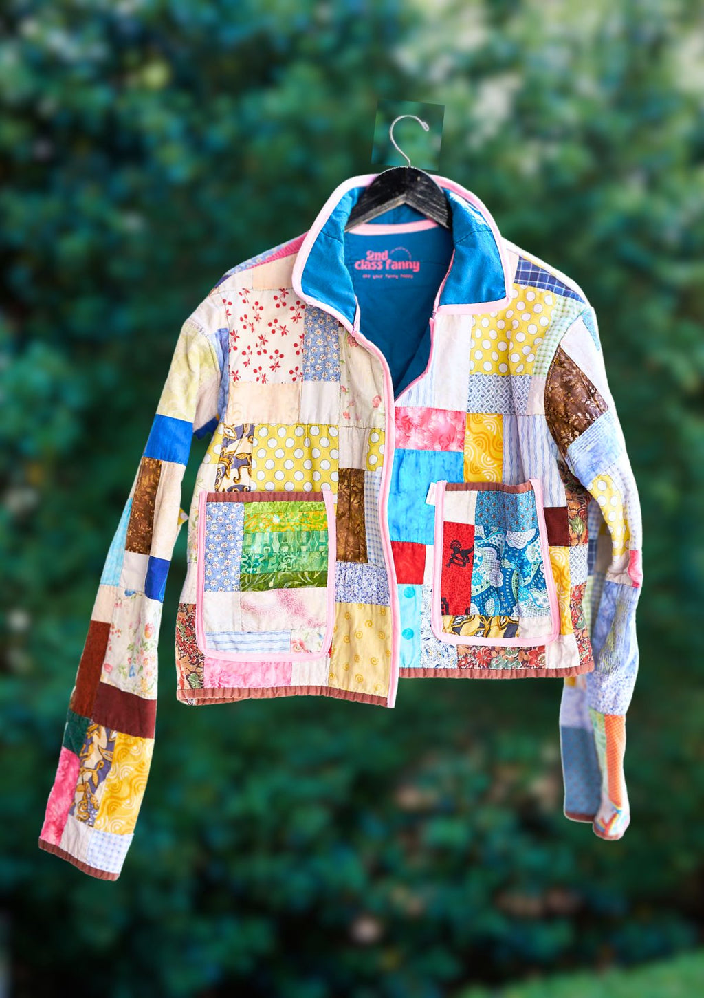 Colorful patchwork jacket hanging against a green leafy background