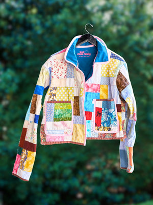 Upcycled Quilt reworked into 2CF signature Every Body Crop Jacket blurred trees in the background.