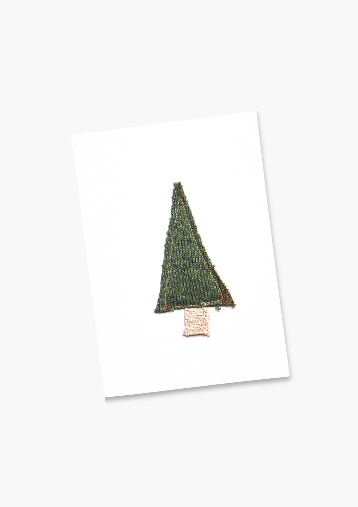 Knitted Christmas tree decoration on a white card with a white background