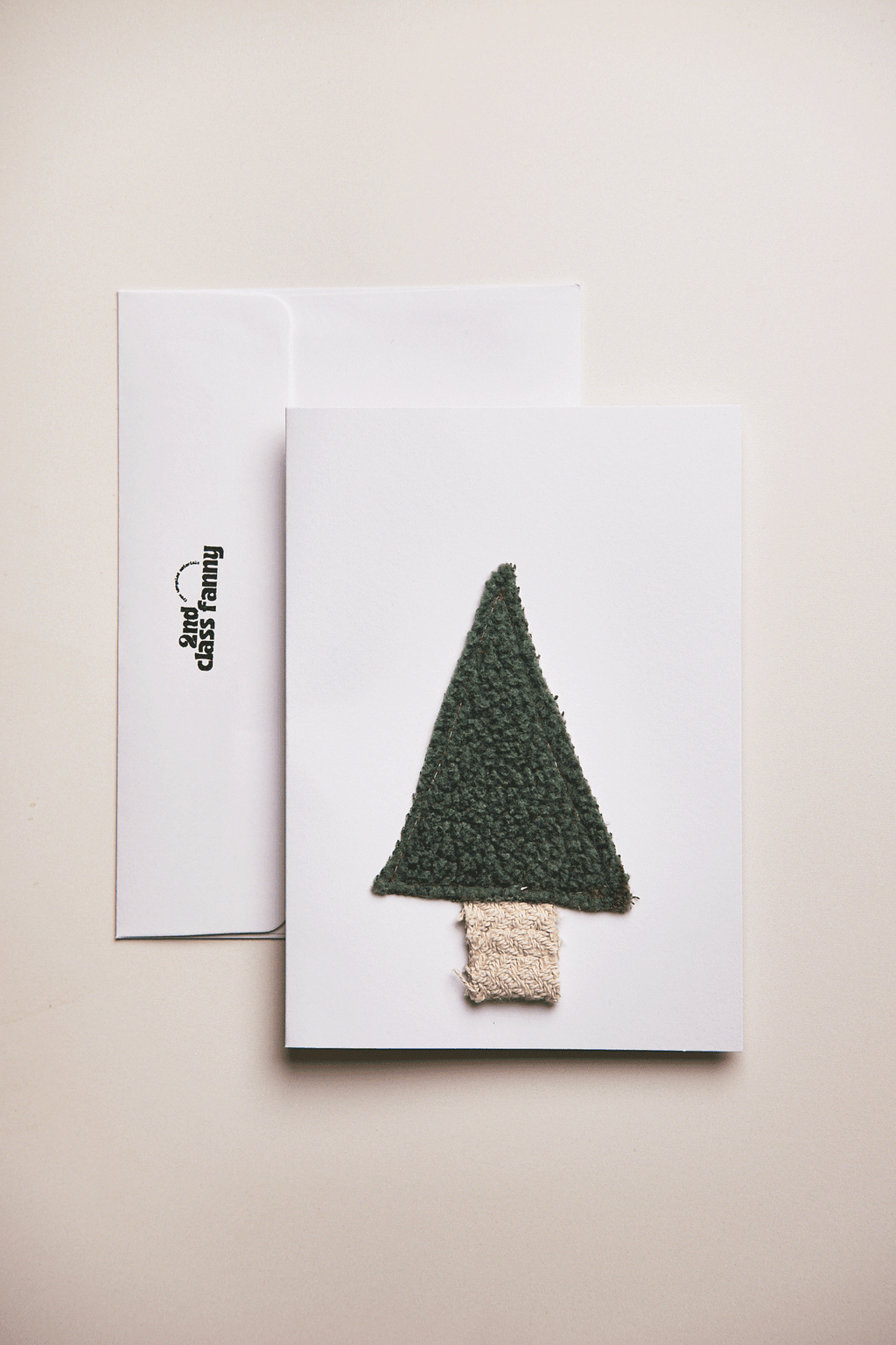 Knitted Christmas tree decoration on a white card with a beige background