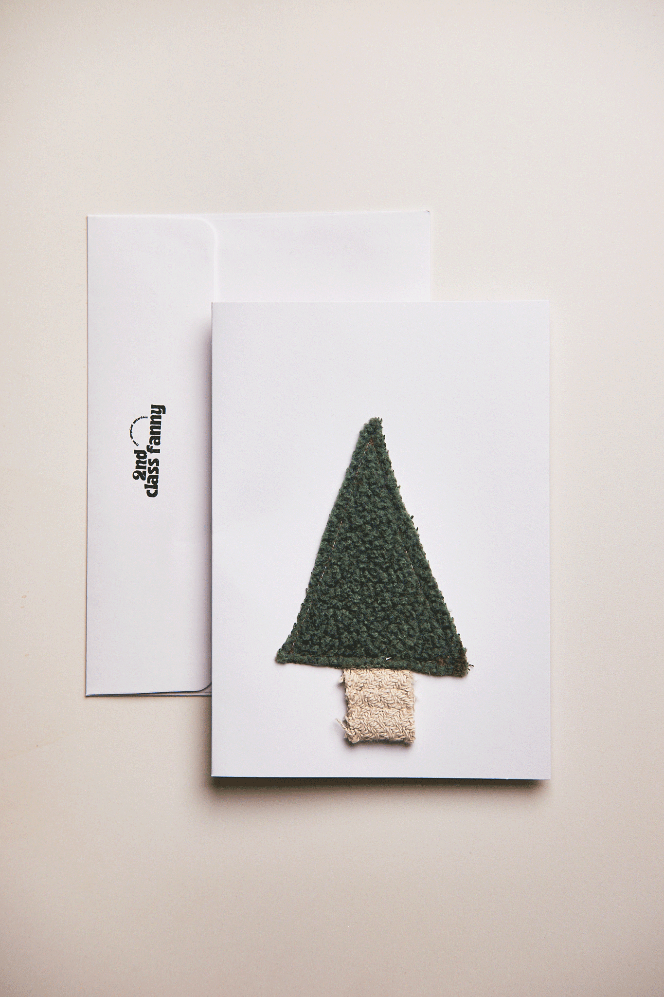 Knitted Christmas tree decoration on a white card with a beige background