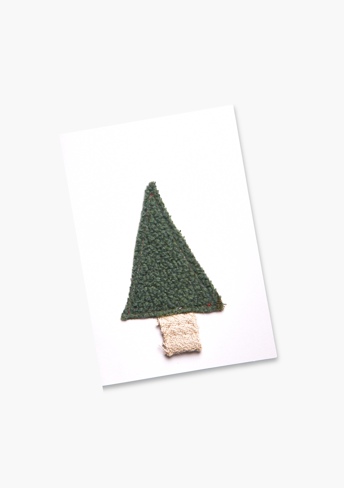 Green textured christmas tree made of fabric on a white card with a white background