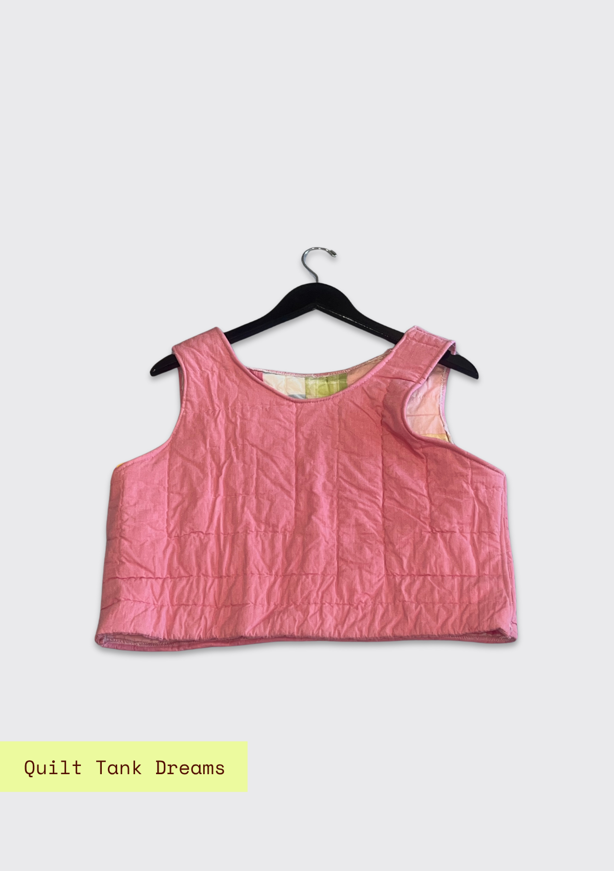 Pink quilted tank top on a hanger with a light pink background