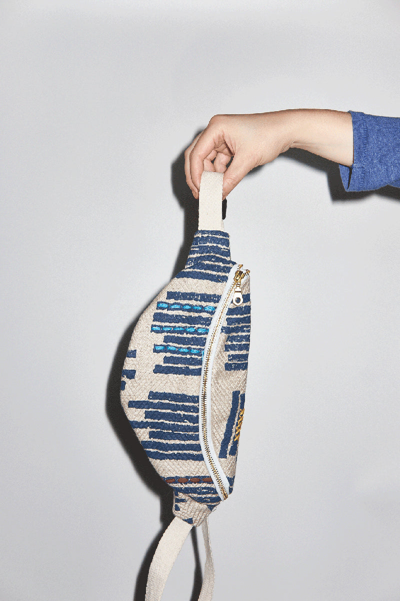 Hand holding a patterned fanny pack against a plain background