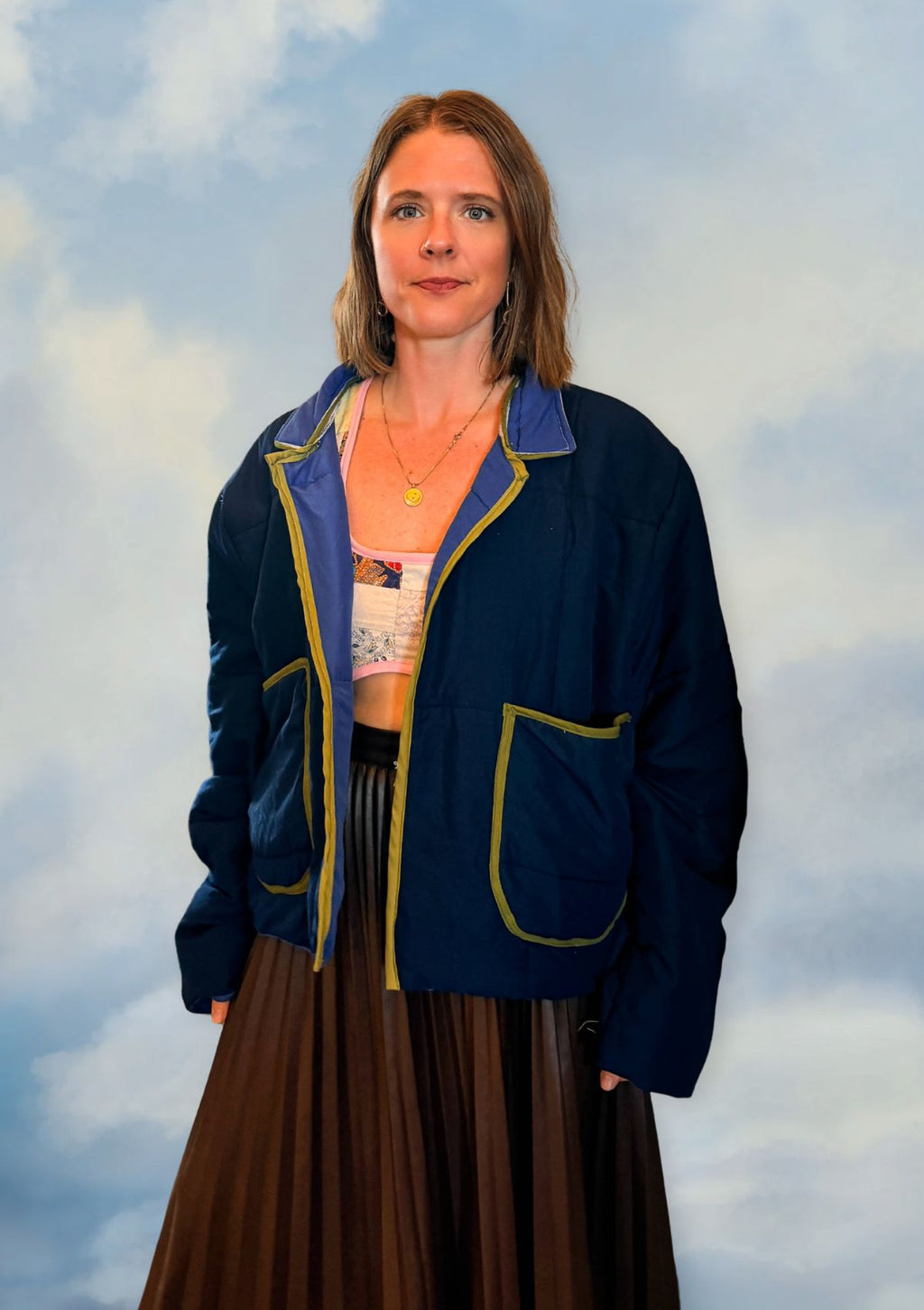 Person wearing a blue puffer jacket from upcycled comforter with yellow accents against a cloudy sky background