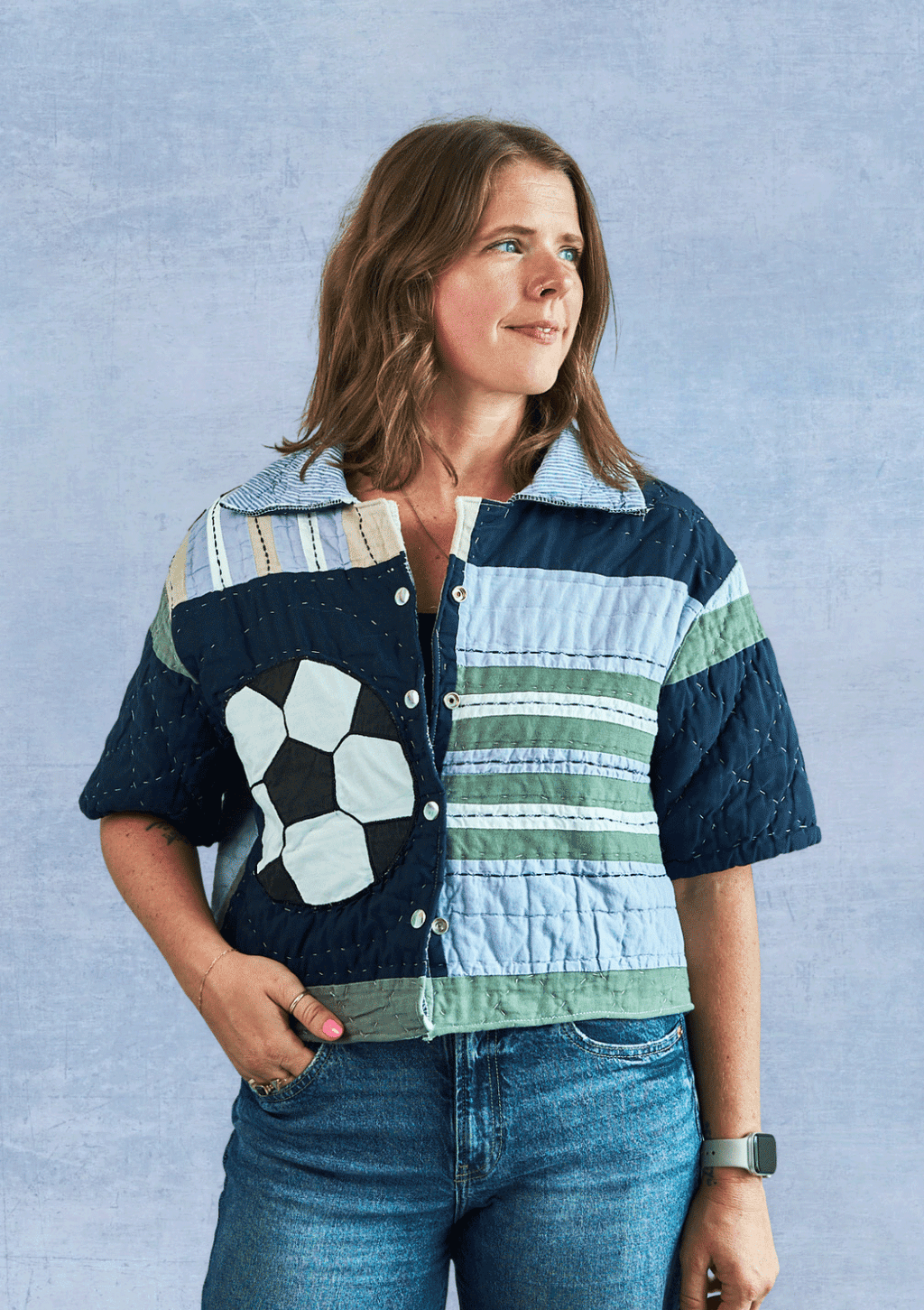 Woman wearing a patchwork jacket, upcycled from a quilt, with a blue background