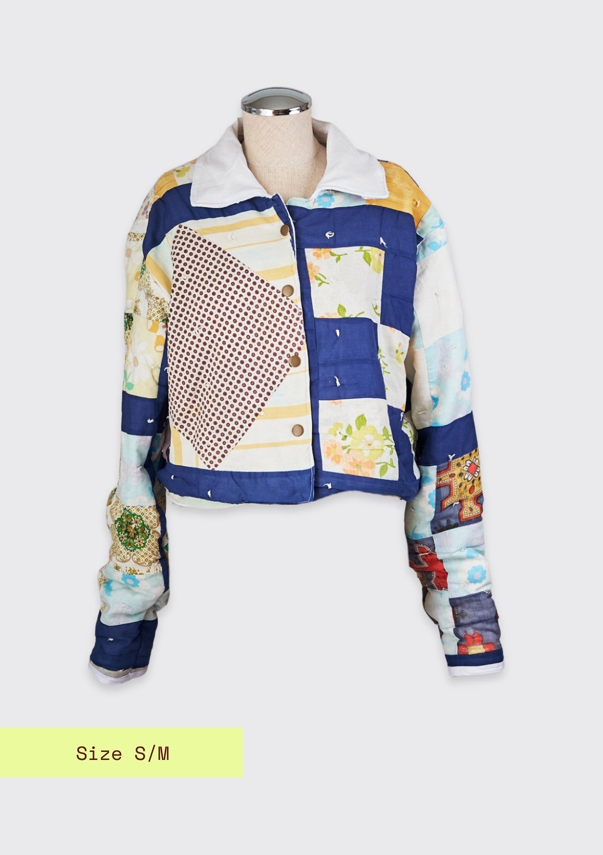 Multicolored patchwork jacket upcycled from a quilt on a mannequin with size S/M label.