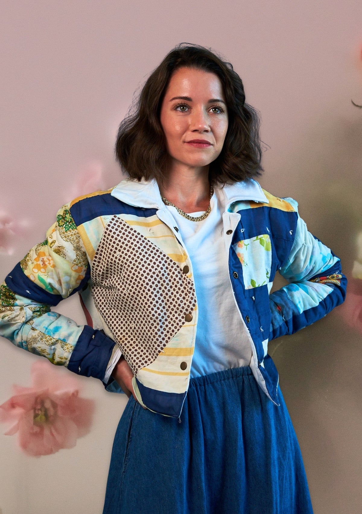 Woman wearing a colorful upcycled quilted jacket with a floral background