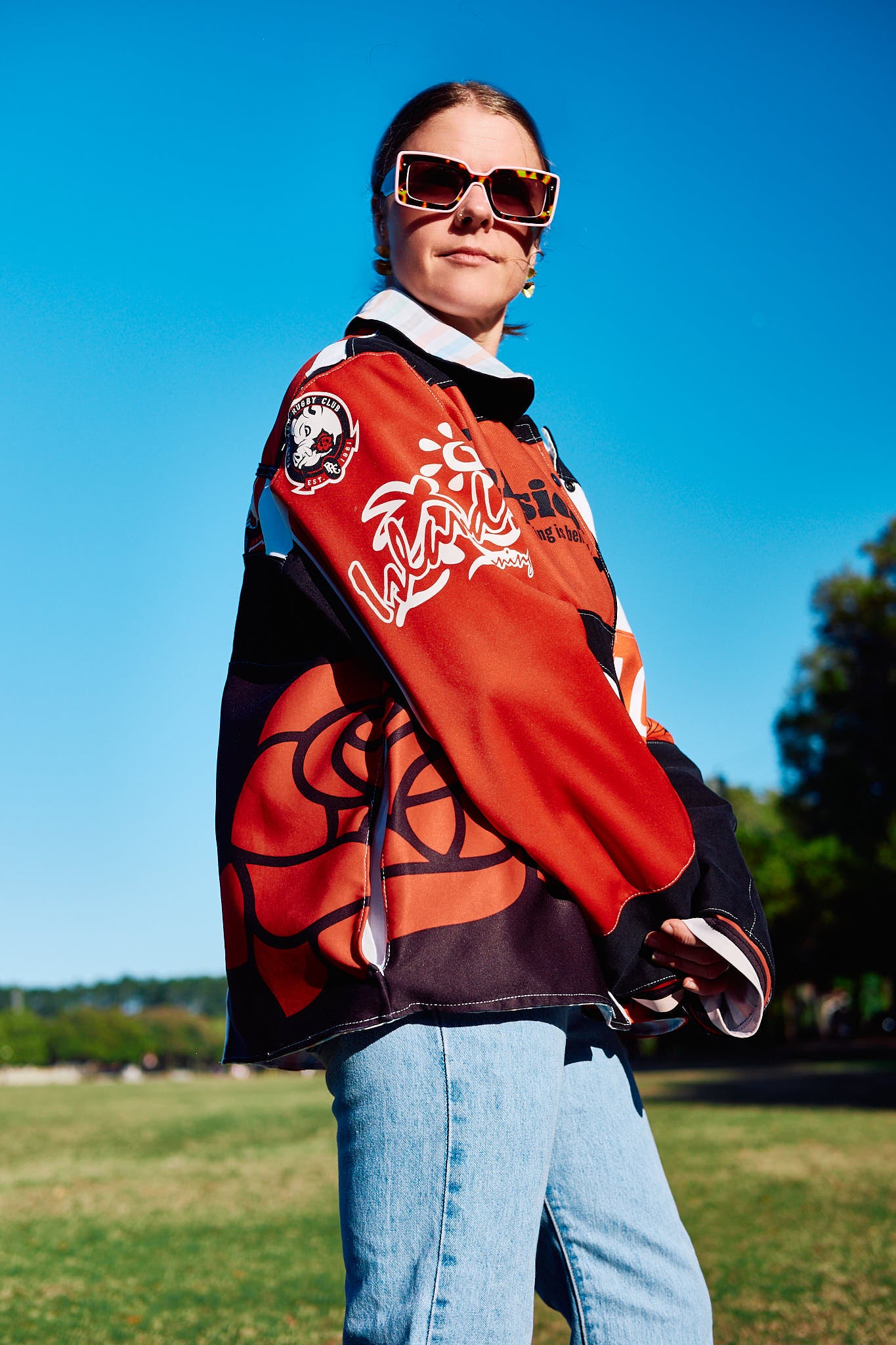 Person wearing a colorful jacket ,upcycled from Portland Pigs Woman's Rugby Team Jersery's, outdoors on a sunny day.