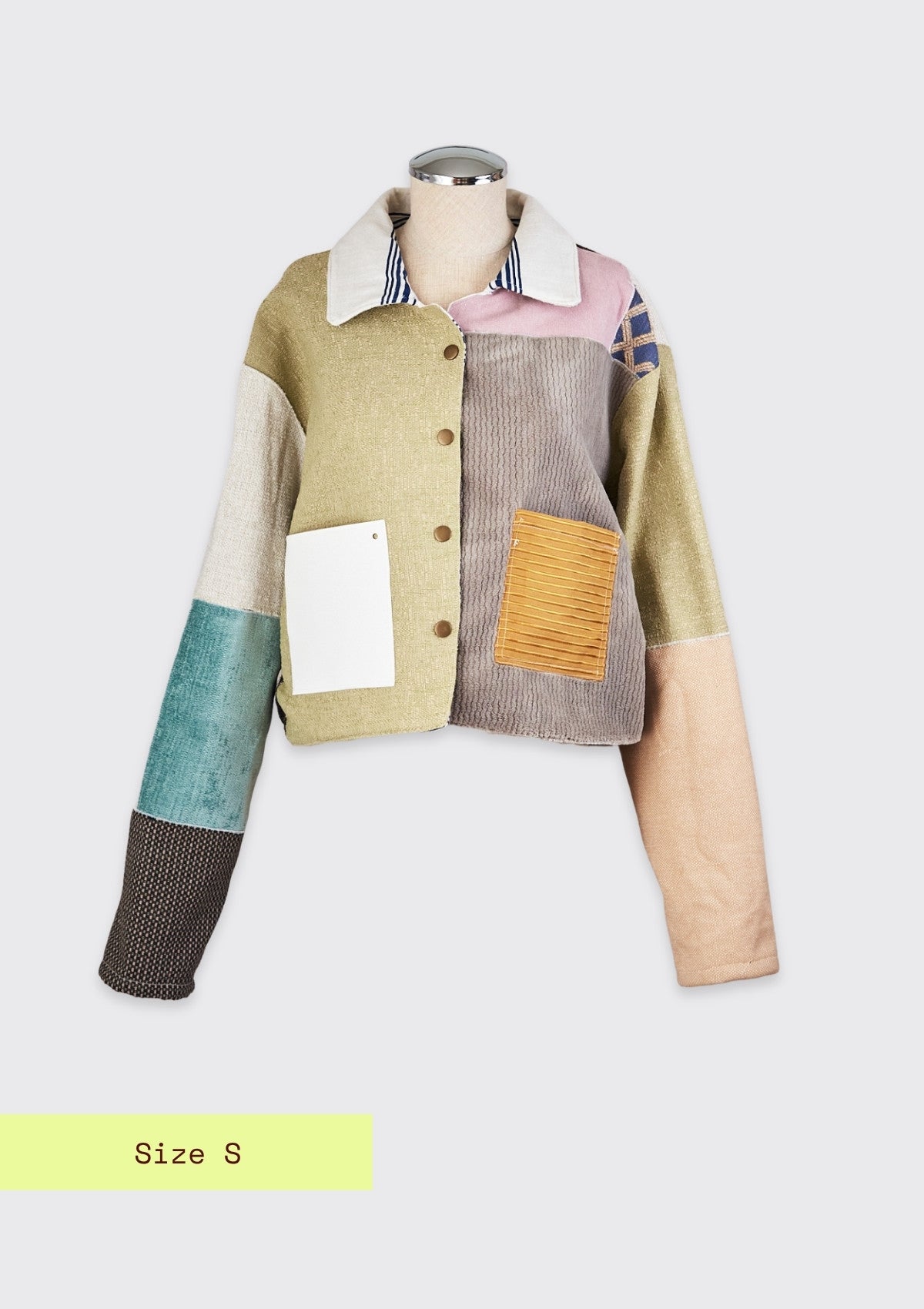 Color-blocked jacket upcycled from upholstery swatches on a mannequin with a white background