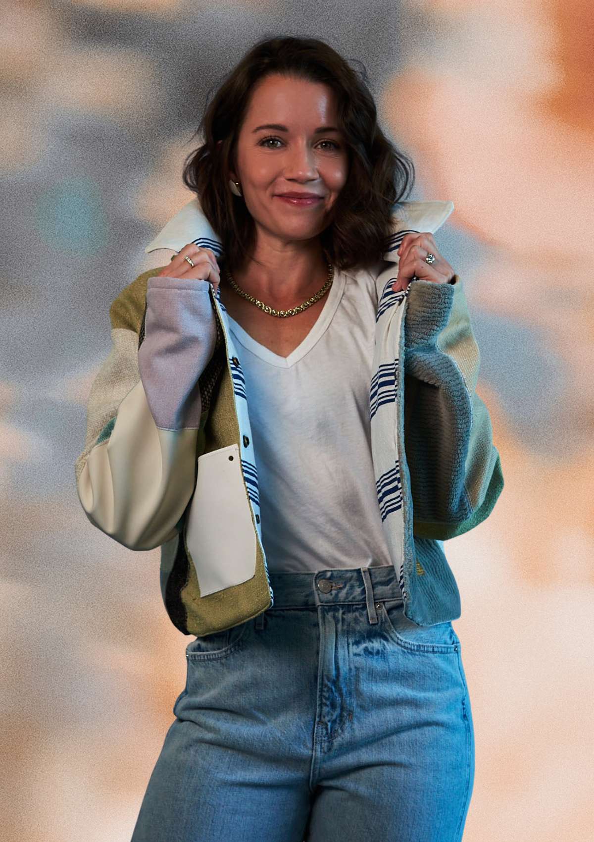 Woman wearing a patchwork jacket, upcycled from upholstery swatches, white shirt, and blue jeans with a blurred background