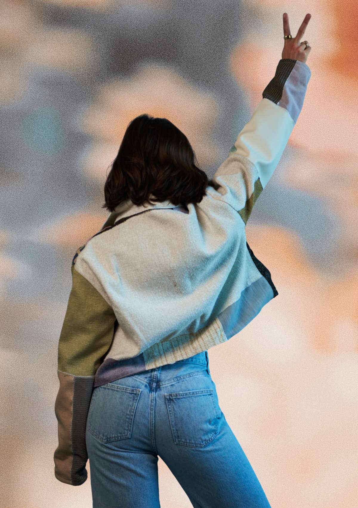 Person wearing a light-colored patchwork jacket with green sleeves, upcycled from upholstery swatches standing against a blurred background