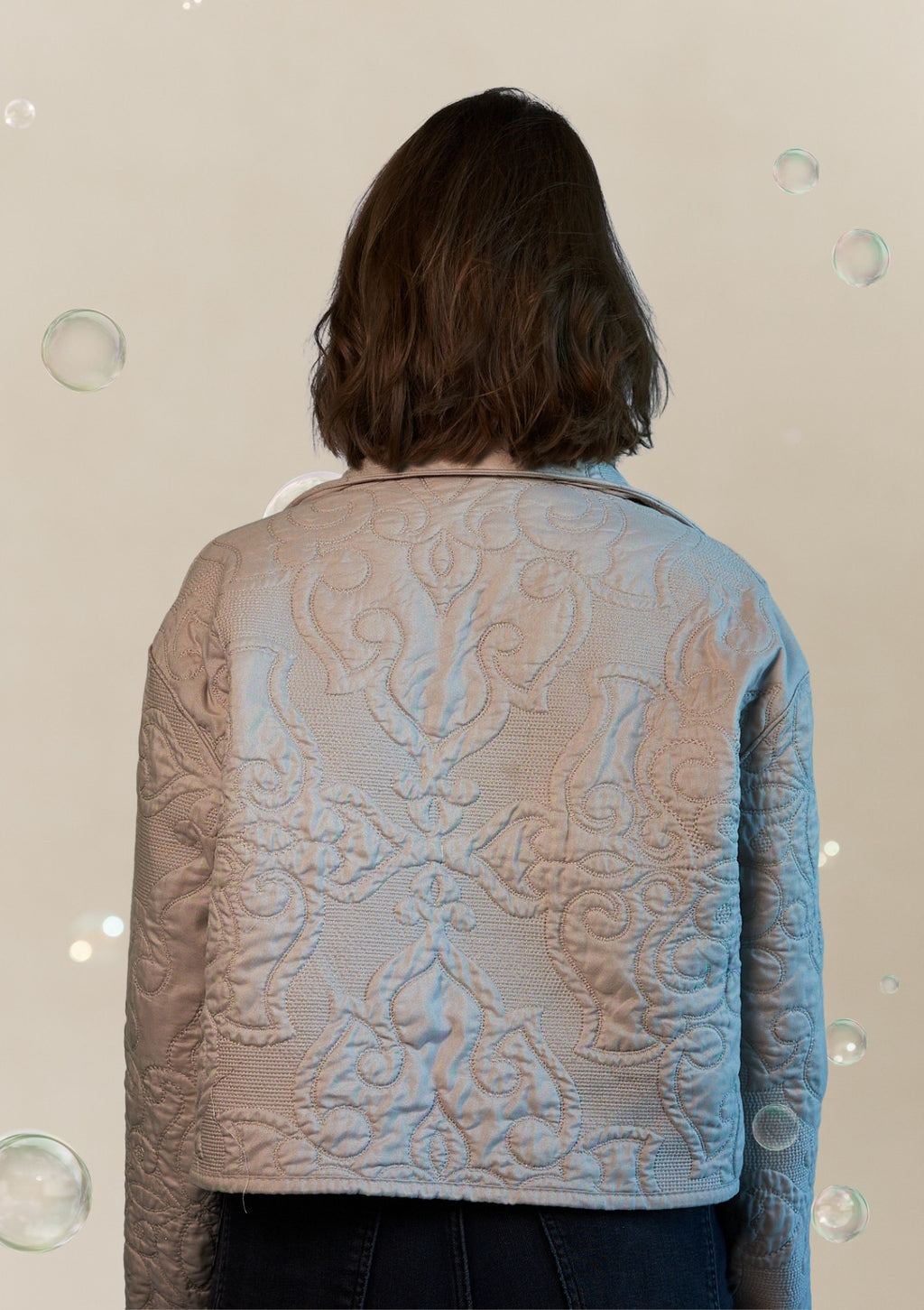 Person wearing a textured jacket upcycled from a comforter with a neutral background