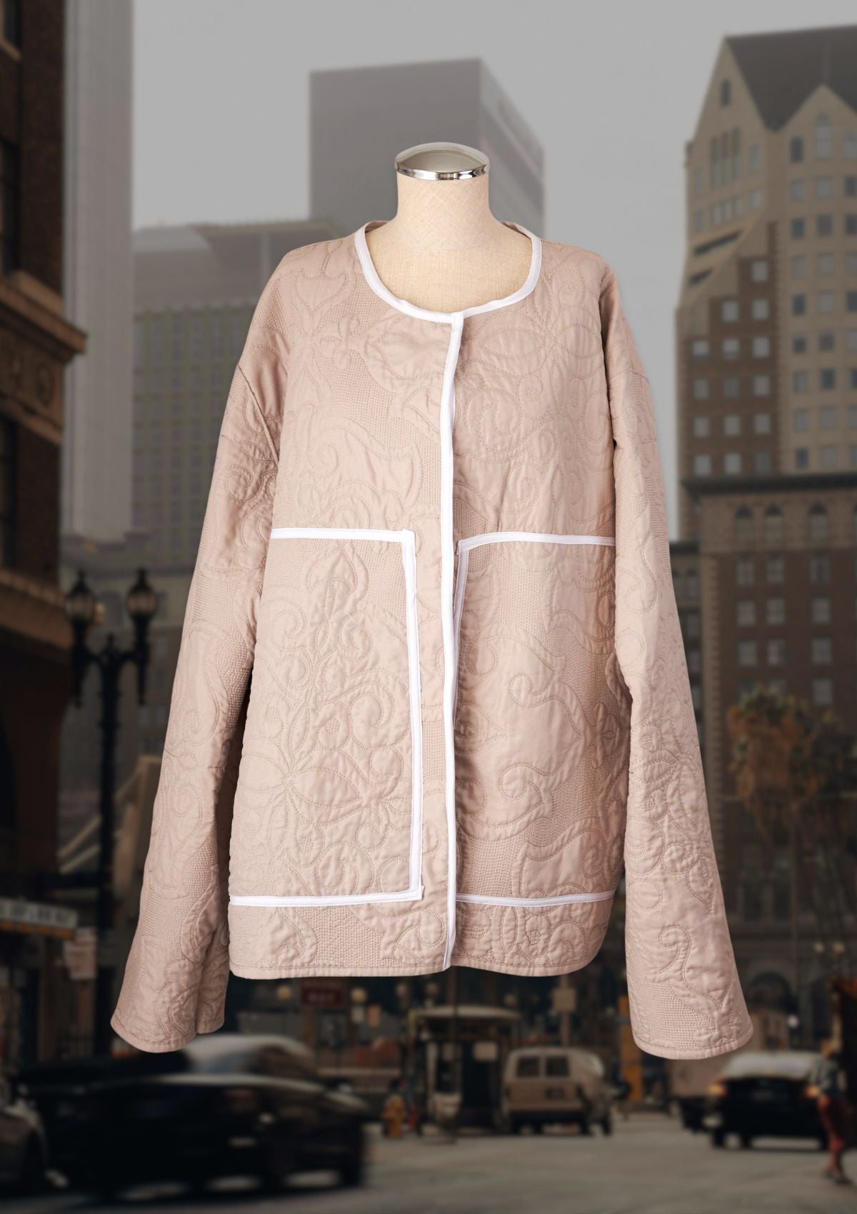 Upcycled beige quilt coat on a mannequin with a cityscape background