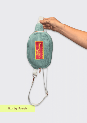 Fanny pack upcycled from a towel with a pink label held by a hand on a white background
