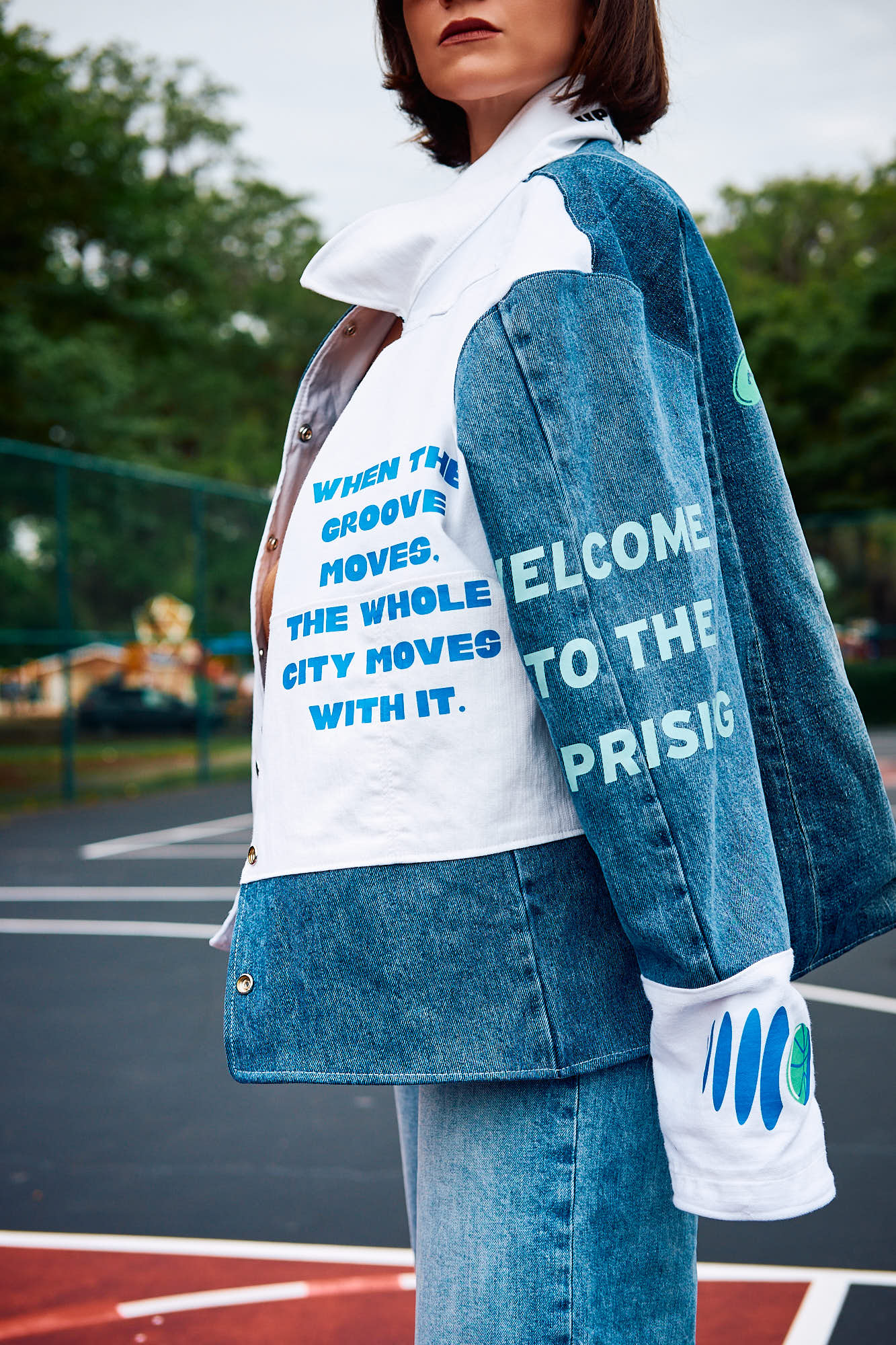 Person wearing a denim jacket with text 'When the Groove Moves, the whole city moves with it' and on a sports court background