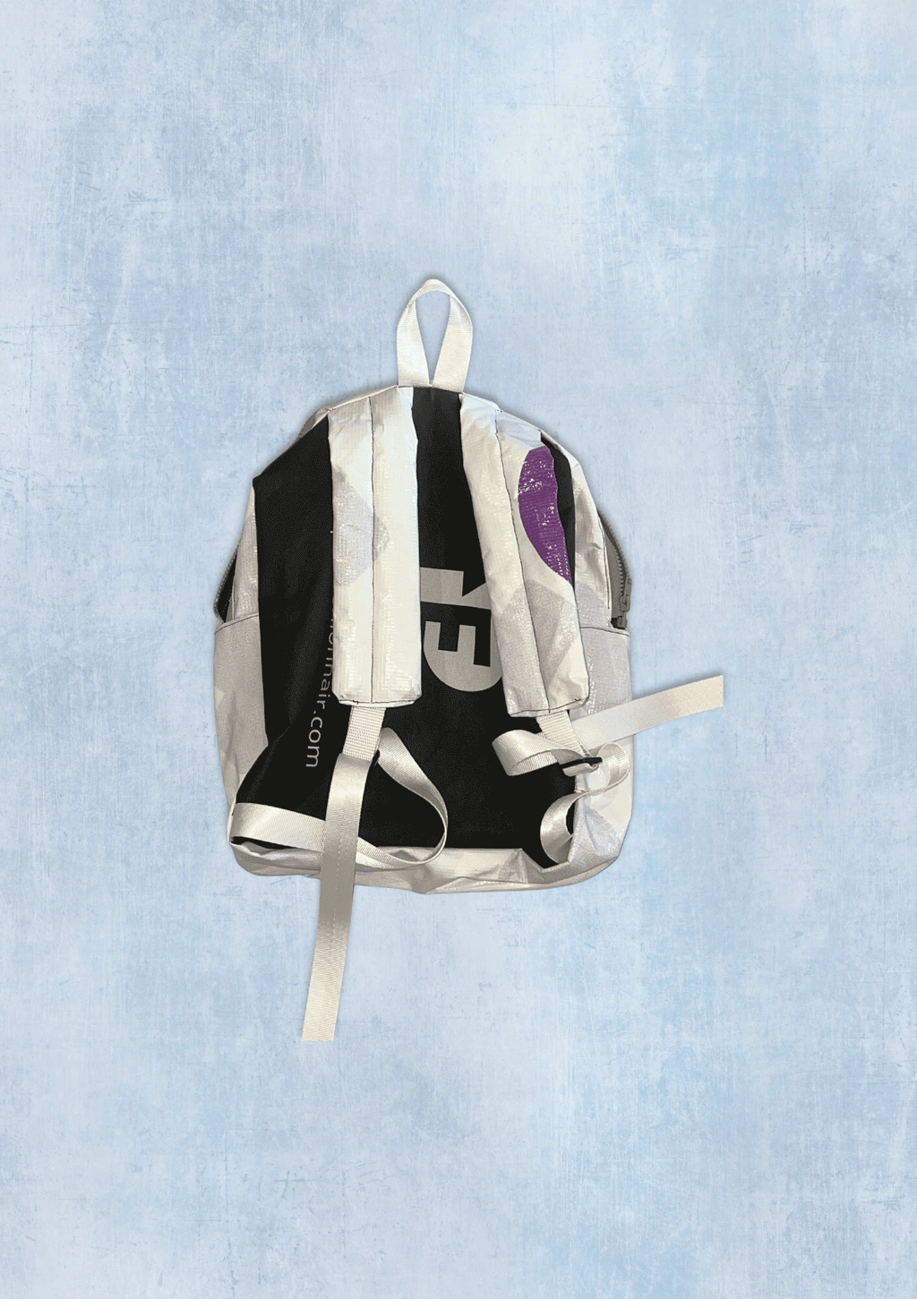 Backpack upcycled from a billboard vinyl with visible branding on a light blue textured background