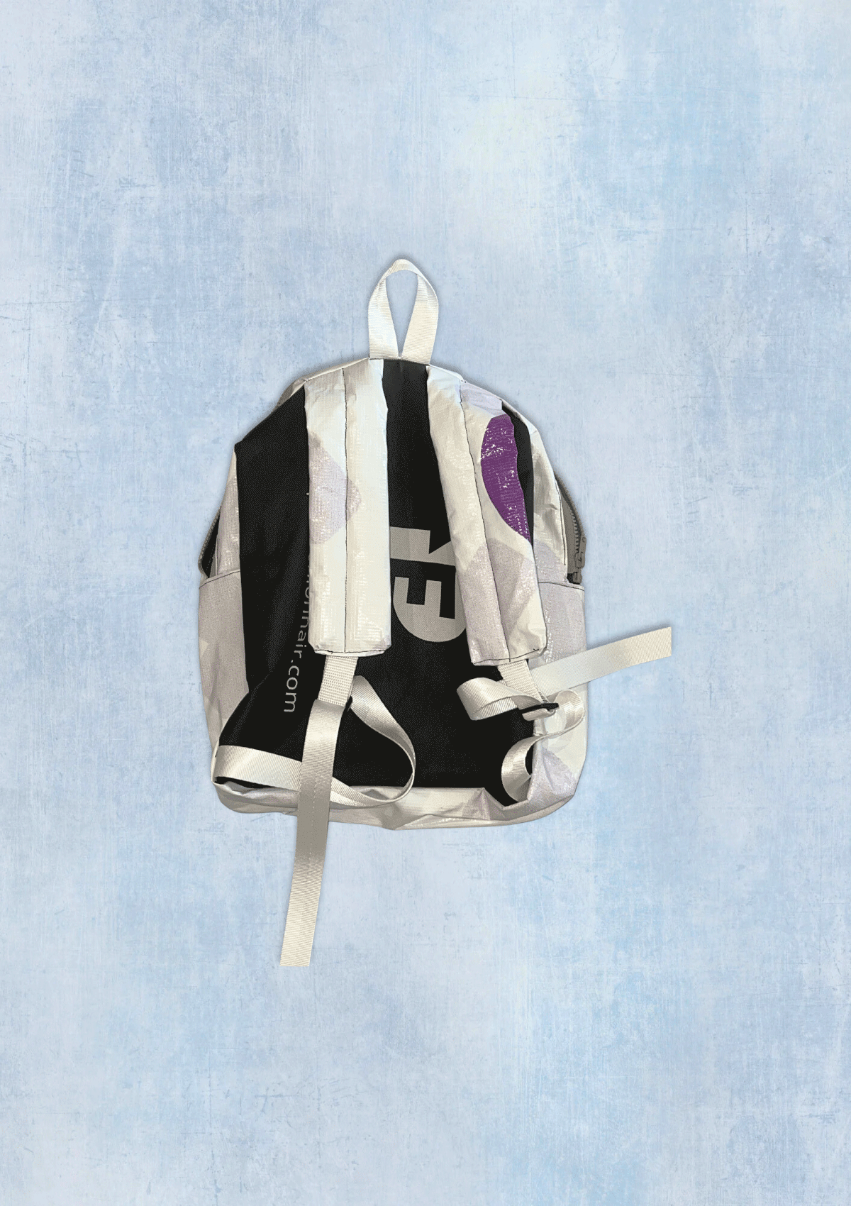 Backpack upcycled from a billboard vinyl with visible branding on a light blue textured background