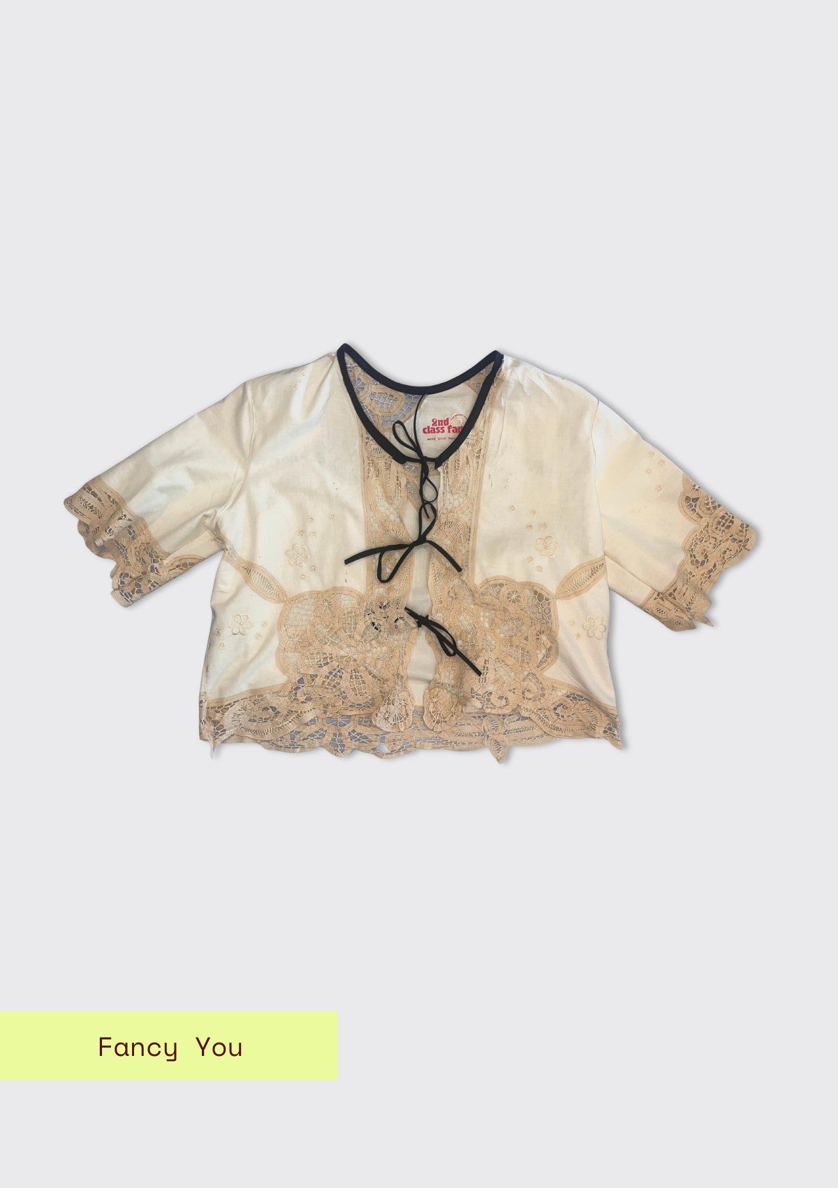 Beige lace top with black ties on a white background