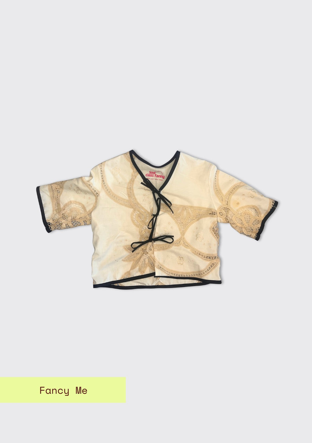 Beige blouse with black trim on a light gray background