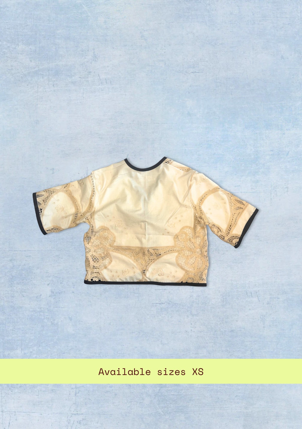 Beige lace top on a light blue textured background with 'Available sizes XS' text.