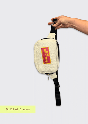 White quilted bag with a pink label "2nd Class Fanny held by a hand on a grey background