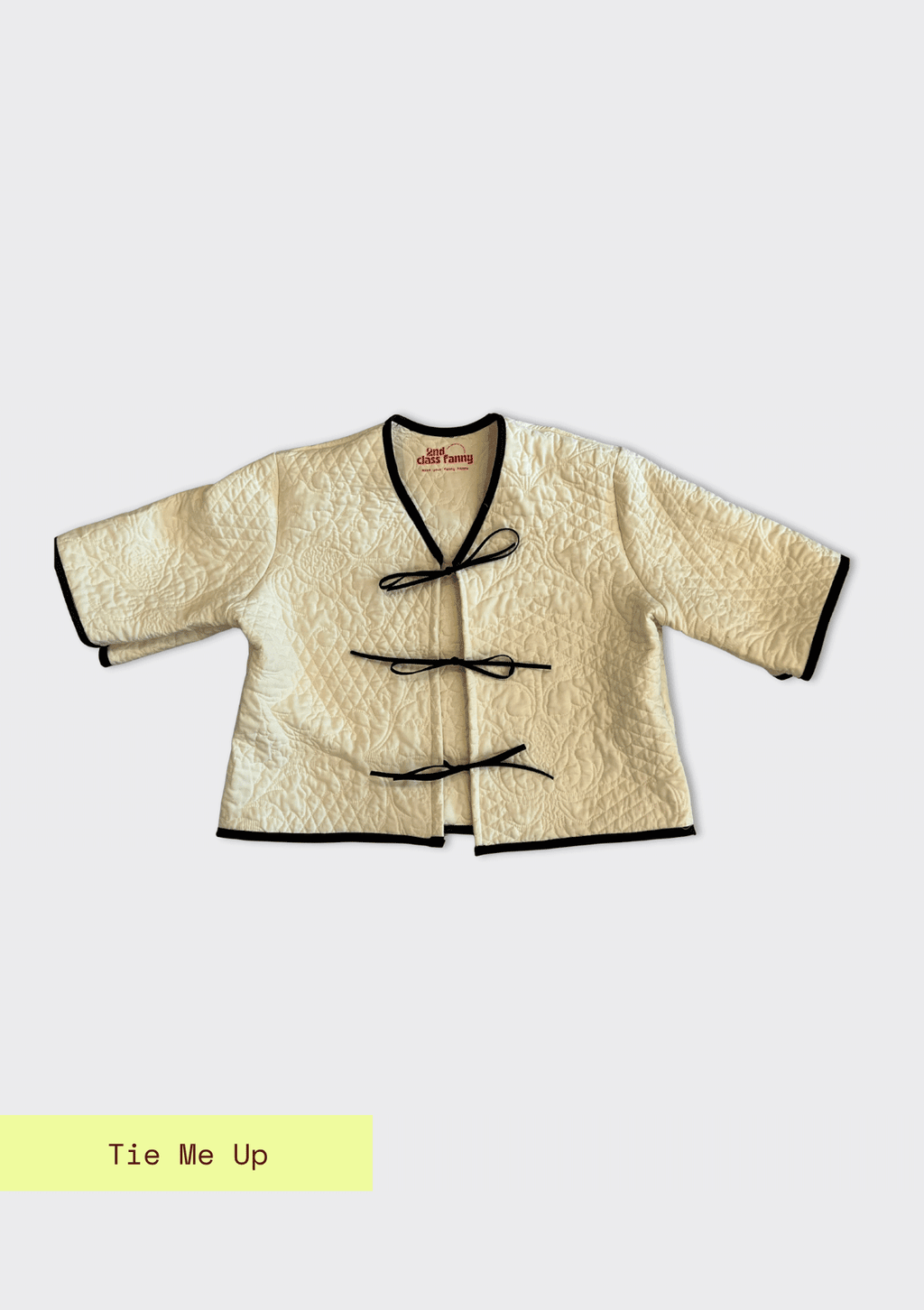 Traditional-style jacket upcycled from a quilt with black trim on a white background