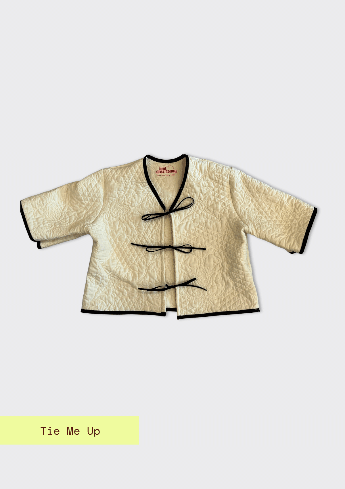 Traditional-style jacket upcycled from a quilt with black trim on a white background