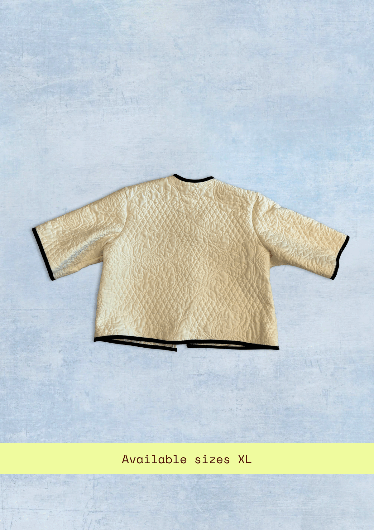 White jacket upcycled from a quilt on a light blue background with text indicating size XL.