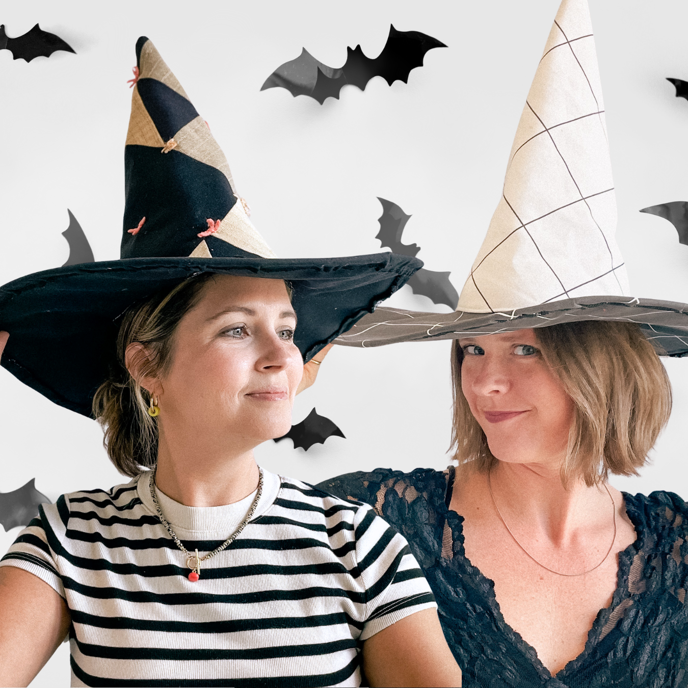 Two women wearing witch hats with a Halloween-themed background featuring bats.