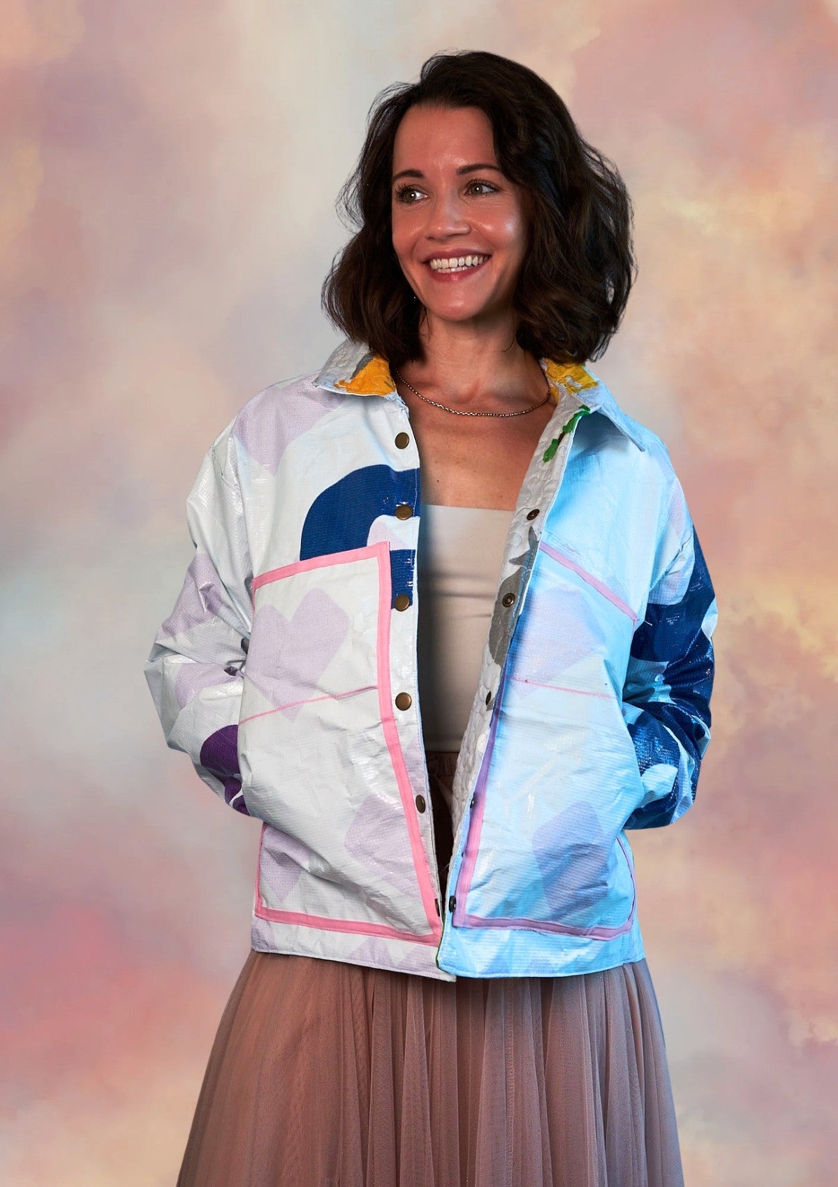 Woman wearing a white jacket with pink lined pockets ucpcyled from billboard with a pastel background