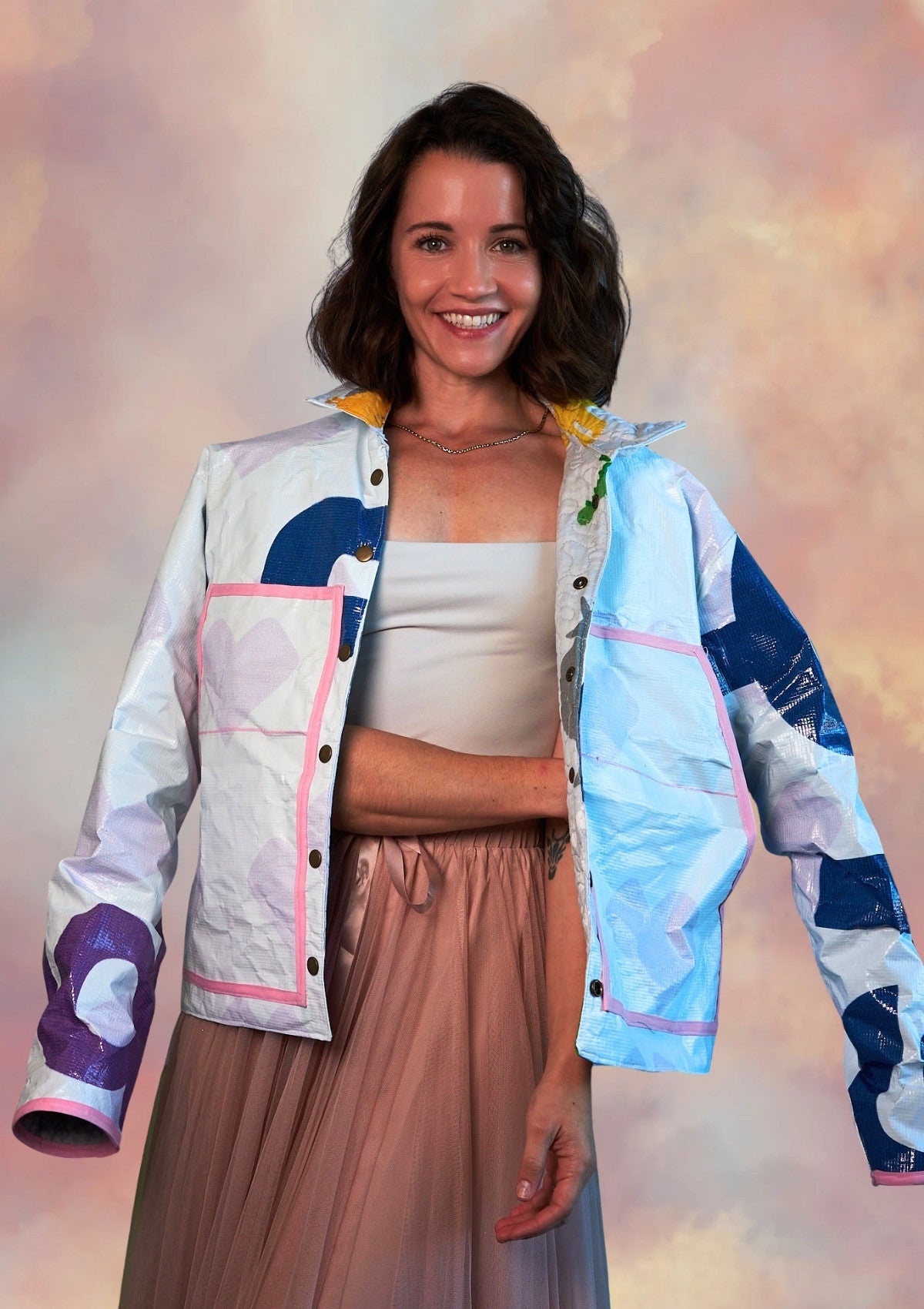 Person wearing a white coat ucpcyled from billboard with pink lined front pockets and a pink tulle skirt on a grey background
