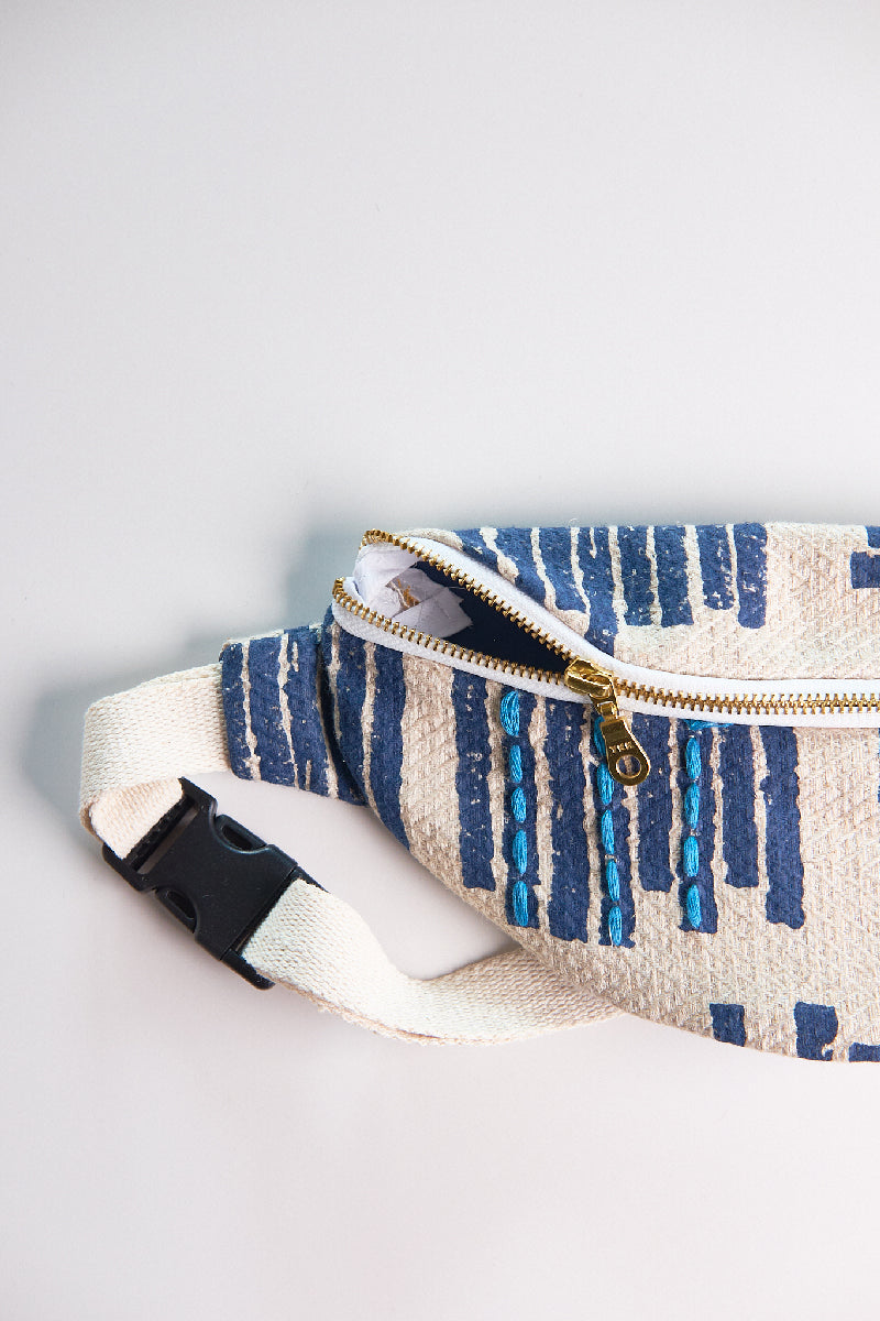 Fabric pouch with blue pattern and white strap on a light gray background