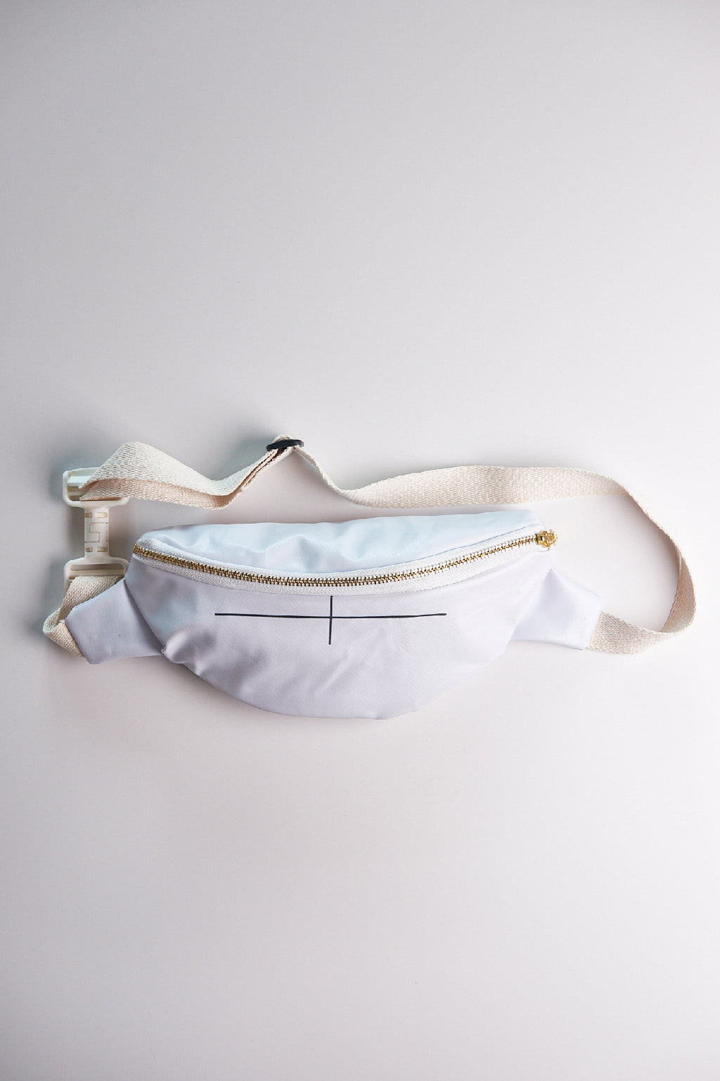 White waist bag with gold zipper on a light gray background
