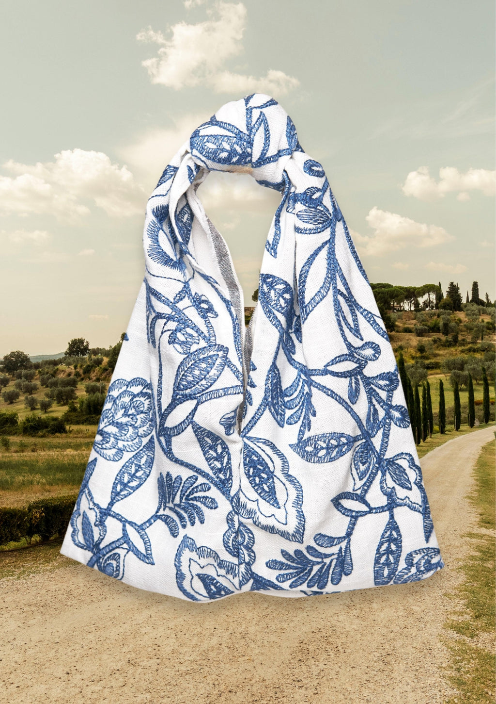 Blue floral patterned Knot Bag, upcycled from deadstock fabric, on a path with a scenic background
